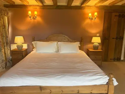 a bedroom with a large white bed with two lamps at Potton Hall in Saxmundham