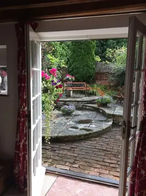 an open door leading to a patio with flowers at The Garden Barn, Manuden nr Stansted in Manuden