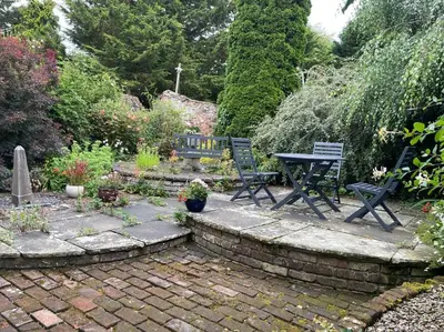 a patio with two chairs and a picnic table in a garden at The Garden Barn, Manuden nr Stansted in Manuden