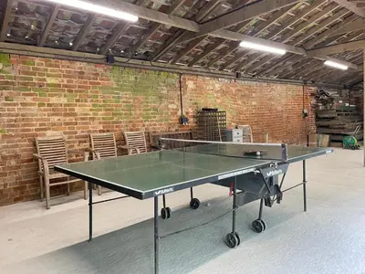 a ping pong table in a room with a brick wall at The Stables, Hasketon in Debach