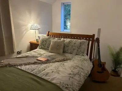 a bedroom with a bed with a guitar next to it at Little Brook Retreat in Chelmsford