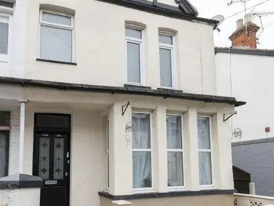 a white house with a black door and windows at Cosy Flat in Leigh Sea View - Pass the Keys in Southend-on-Sea