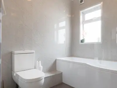 a white bathroom with a toilet and a bath tub at Cosy Flat in Leigh Sea View - Pass the Keys in Southend-on-Sea