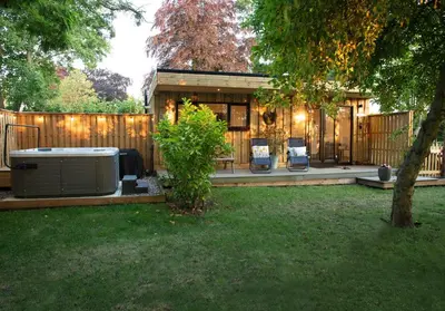 a backyard with a hot tub and two chairs at Copper Beech Lodge with Hot Tub, Games Room, Fire Pit in Toppesfield