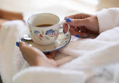 a woman is holding a cup of coffee at Copper Beech Lodge with Hot Tub, Games Room, Fire Pit in Toppesfield