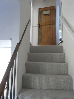 a stairway with a wooden door in a house at Blythburgh Cottage, Yoxford in Yoxford