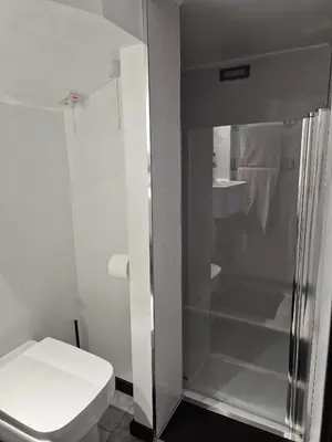 a white bathroom with a shower and a toilet at Secret Bunker at Vikings Forge in Bury Saint Edmunds