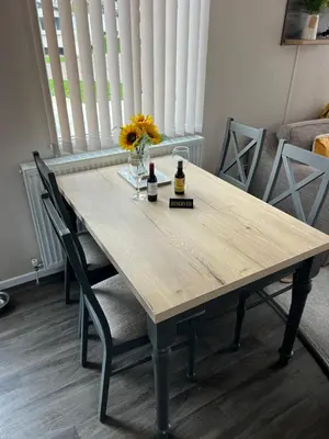 a wooden table with two bottles and a vase of flowers at Mimosa lodge in Little Clacton