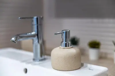 a bathroom sink with two faucets and a soap dispenser at The Essex Apartments - Ashby House in Chelmsford