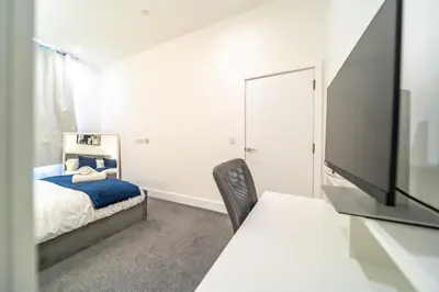 a bedroom with a bed and a flat screen tv at The Essex Apartments - Ashby House in Chelmsford