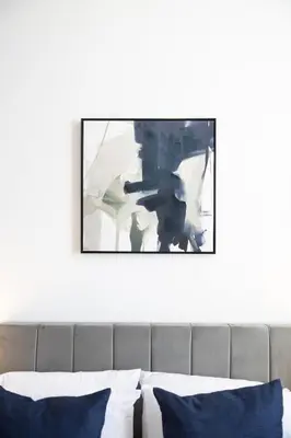 a picture hanging above a bed in a bedroom at The Essex Apartments - Ashby House in Chelmsford
