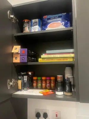 a cabinet filled with lots of food and books at The Essex Apartments - Ashby House in Chelmsford