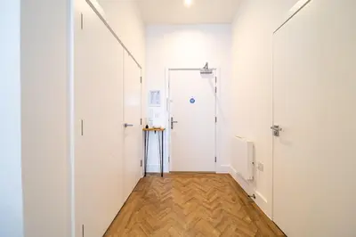a hallway with white walls and a wooden floor at The Essex Apartments - Ashby House in Chelmsford