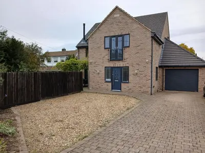 a brick house with a blue door and a fence at Woodlands Peaceful Bedrooms in Hemingford Grey