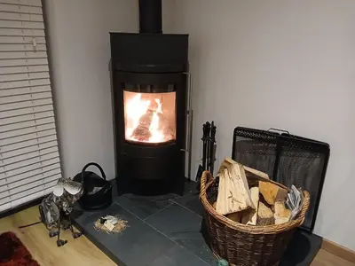 a living room with a fireplace with a basket of wood at Woodlands Peaceful Bedrooms in Hemingford Grey