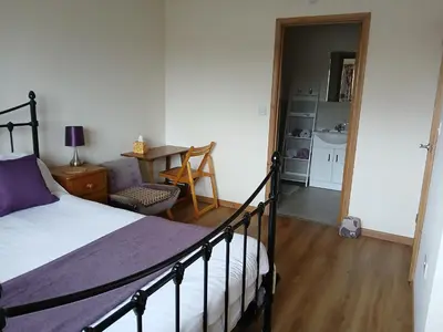a bedroom with a bed and a table and a kitchen at Woodlands Peaceful Bedrooms in Hemingford Grey