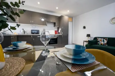 a dining table with a wine glass and a kitchen at Suffolk Square in Sudbury