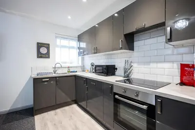 a kitchen with black cabinets and a sink at Suffolk Square in Sudbury