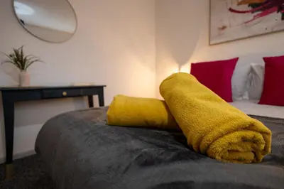 a yellow towel laying on top of a bed at Suffolk Square in Sudbury