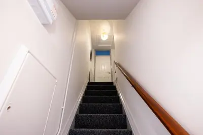 a hallway with stairs leading up to a white door at Suffolk Square in Sudbury