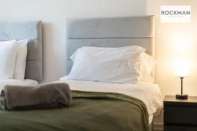 a bed with white sheets and pillows next to a lamp at Library House Apartments - FREE PARKING - Contractor Hub - Superfast Wi-Fi - Long Term Stays in Brentwood