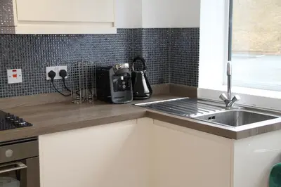 a kitchen with a sink and a counter top at Colchester town and castle modern flat with kitchen & private parking in Hythe