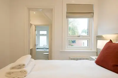 a bedroom with a white bed and a window at Millicent Cottage, Aldeburgh in Aldeburgh