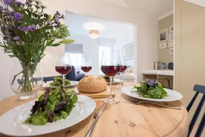 a wooden table with two plates of food and wine glasses at Millicent Cottage, Aldeburgh in Aldeburgh