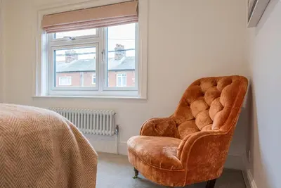 a chair sitting in a room next to a window at Millicent Cottage, Aldeburgh in Aldeburgh