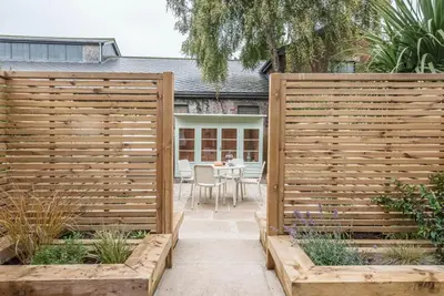 a wooden fence in a garden with a table at Millicent Cottage, Aldeburgh in Aldeburgh