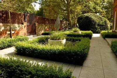 a garden with green bushes and a fence at Kingsfield House, Aldeburgh in Aldeburgh