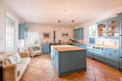 a large kitchen with blue cabinets and a couch at Kingsfield House, Aldeburgh in Aldeburgh