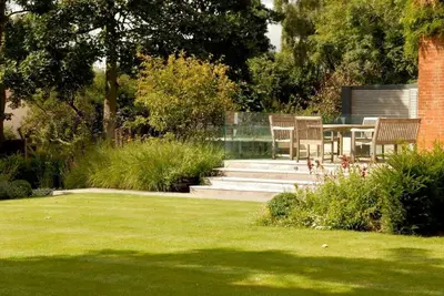 a garden with chairs and a table in the grass at Kingsfield House, Aldeburgh in Aldeburgh