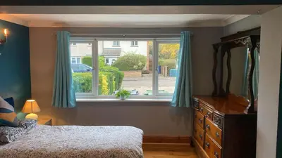 a bedroom with a bed and a window with blue curtains at Warm and Homely 4 Bed house w big Garden & Parking in Milton