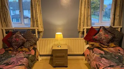 a living room with two beds and a lamp on a table at Warm and Homely 4 Bed house w big Garden & Parking in Milton