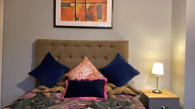 a bedroom with a bed with blue pillows at Warm and Homely 4 Bed house w big Garden & Parking in Milton