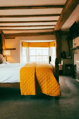 a large yellow bed in a room with a window at The George in Cavendish