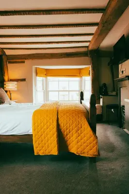 a large yellow bed in a room with a window at The George in Cavendish