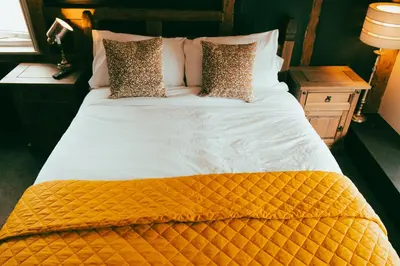 a large bed with an orange and white comforter and pillows at The George in Cavendish