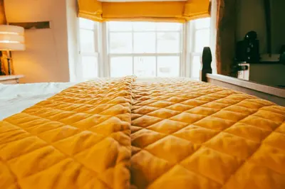 a large yellow bed in a room with a window at The George in Cavendish