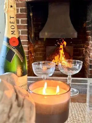 a bottle of champagne and candles on a table with a fireplace at Perfect country cottage retreat! in Fyfield