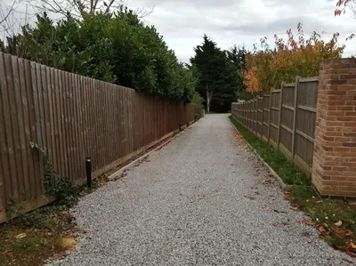 a fence next to a gravel road next to a fence at The Highlands - 5 bed 5 bath - Huge Sociable House in Exning