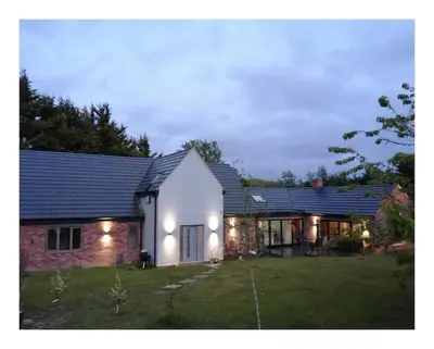 a white house with lights on it in a yard at The Highlands - 5 bed 5 bath - Huge Sociable House in Exning