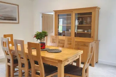 a wooden dining room table with chairs and a cabinet at The Highlands - 5 bed 5 bath - Huge Sociable House in Exning
