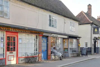 a man sitting in a chair in the window of a store at Host My Nest - Historic 1BR 20 Mins to Stansted in Sawbridgeworth
