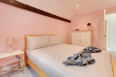 a bedroom with a white bed and a white table at Host My Nest - Historic 1BR 20 Mins to Stansted in Sawbridgeworth