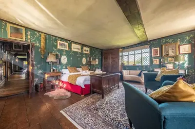 a bedroom with green wallpaper with a bed and a fireplace at Spectacular thousand year old Medieval manor house - Flemings Hall in Ipswich