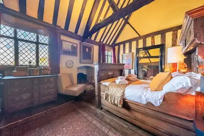 a bedroom with a bed and a chair in it at Spectacular thousand year old Medieval manor house - Flemings Hall in Ipswich