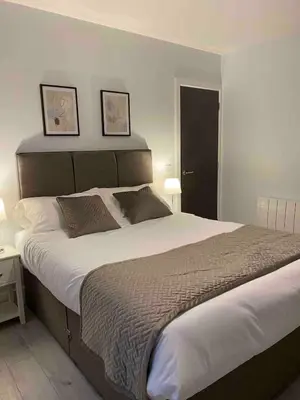 a large bed in a bedroom with two pictures on the wall at Dream Yard Apartments Westcliff in Southend-on-Sea