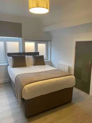 a bedroom with a large bed in a room with windows at Dream Yard Apartments Westcliff in Southend-on-Sea